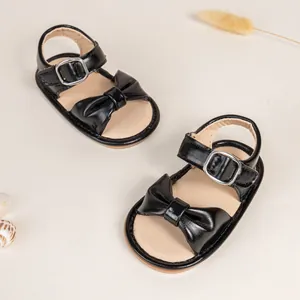Detail of baby girl black leather sandals with large bow and adjustable ankle strap