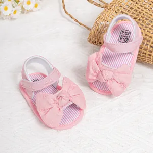 Detail view of pink baby sandals with floral embroidery and large bow decoration