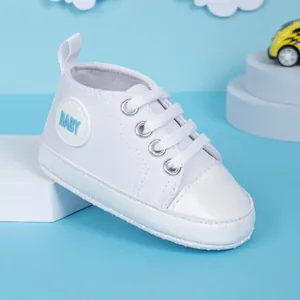 Détail de chaussures bébé en toile blanche avec semelles souples et renfort en cuir