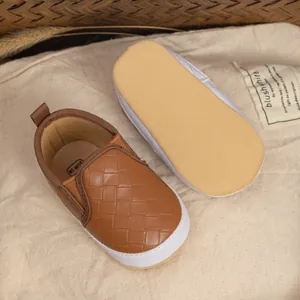 Detailed view of brown woven leather baby slip-on walking shoes with white soft soles