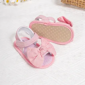 Detail of pink baby sandals with large bow, soft anti-slip sole and velcro strap