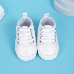Vue de dessus de baskets bébé en toile blanche avec semelles souples et bout renforcé