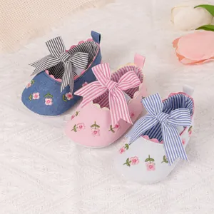 Detailed view of baby girl shoes with striped bows and floral embroidery in three colors
