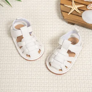 White faux leather baby sandals with breathable woven straps on a summer beach background