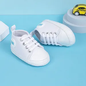 Gros plan de chaussures bébé en toile blanche avec logo bleu et protection d'orteils