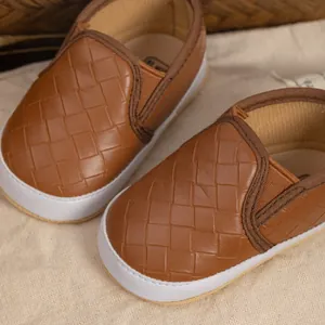 Macro shot of brown woven leather texture on slip-on baby shoes with white rubber sole