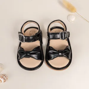 Top view of black baby sandals with bow decoration and size mark for 0-6 months