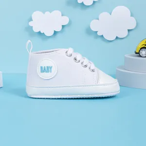 Détail de baskets montantes en toile pour bébé avec semelle souple antidérapante et logo