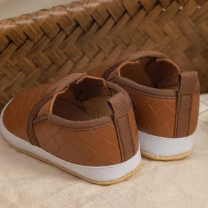 Detailed close-up of woven texture and soft sole on brown slip-on infant walking shoes