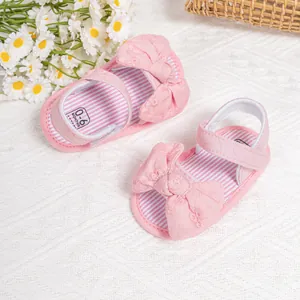 Detail of pink baby sandals with large bow and red striped insole on soft knit texture