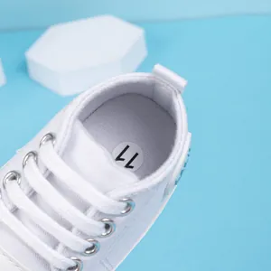 Gros plan détaillé de baskets en toile blanche pour bébé avec étiquette de taille 11