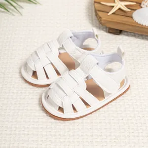 Detail of white faux leather baby sandals with woven straps and hook-and-loop closure