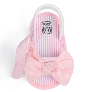 Close-up of pink baby sandal with floral bow and 0-6 months size marking on striped insole