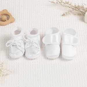 White baby walking shoes with lace details and heart embroidery on soft fabric soles