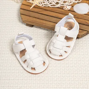 Detail of white woven baby sandals with velcro straps on a summer beach themed background