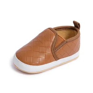 Detail of baby walking shoes with brown geometric woven texture and soft white rubber sole