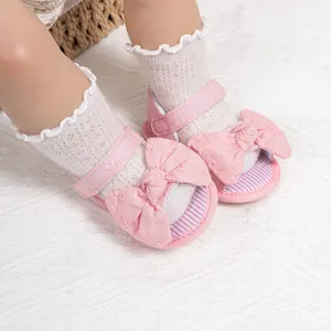 Detailed view of pink baby sandals featuring an embroidered bow and hook-and-loop straps