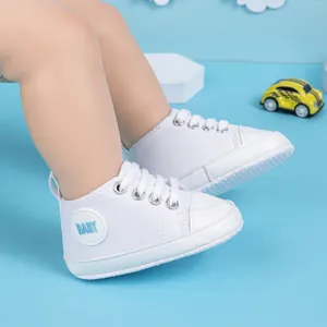 Détail de chaussures montantes en toile blanche pour bébé avec semelle souple et patch bleu