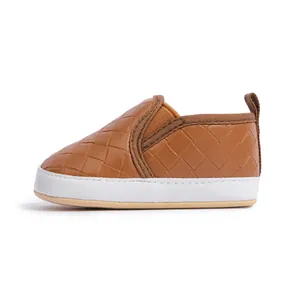 Detail of brown woven faux leather baby slip-on shoes with soft soles and pull tabs