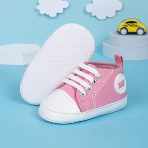 Détail de chaussures bébé en toile rose avec semelle antidérapante et lacets blancs