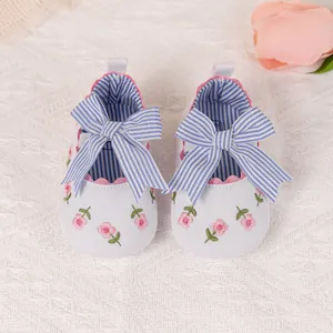 Detail of baby princess shoe with pink flower embroidery and a blue striped bow