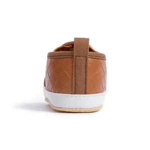Detail view of brown baby shoes featuring woven leather texture and a convenient heel pull tab