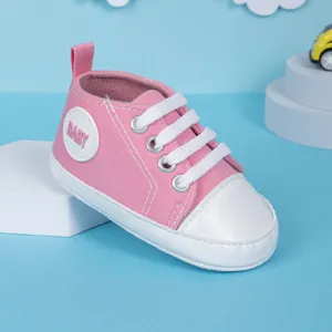 Détail d'une chaussure de marche bébé en toile rose avec bout blanc et logo BABY