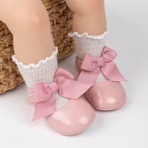 Close-up of pink patent leather baby shoes with large bow and hook-and-loop closure