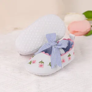 Close-up of baby princess shoes with striped bow, floral embroidery and non-slip sole