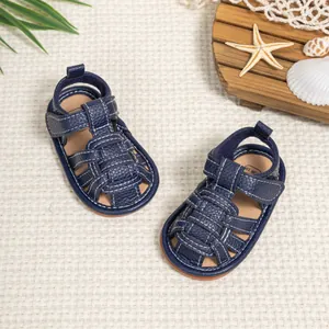 Dark blue baby sandals with woven design and white stitching on a white textured background