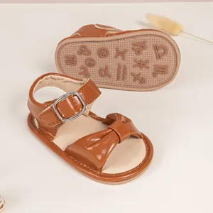 Close-up of brown baby sandal with non-slip rubber sole showing embossed zodiac patterns