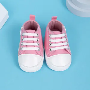 Baskets en toile rose pour bébé sur supports avec semelle souple et lacets blancs
