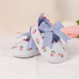Macro detail of baby soft sole shoes with floral embroidery and striped ribbon bow