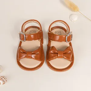 Close-up of brown baby sandals with bow decoration and size EUR 18 printed on the insole