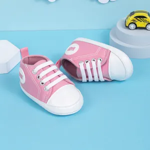 Chaussure de marche bébé en toile rose avec bout blanc et lacets sur fond bleu clair
