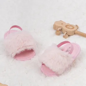 Gros plan de sandales bébé en fausse fourrure rose avec sangle élastique et marquage de taille
