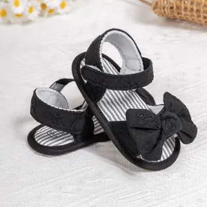 Detail view of black baby sandals with large bow decoration and velcro strap closure