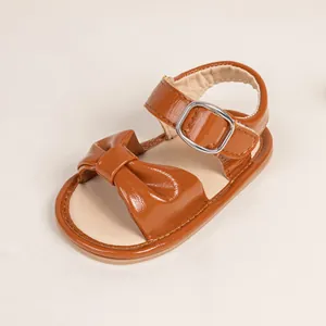Detailed view of brown leather baby sandals featuring a decorative bow and buckle strap