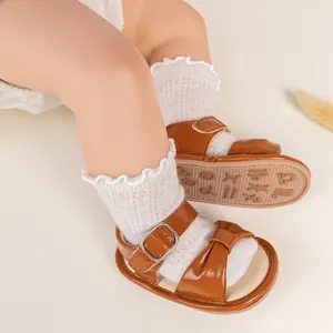 Detail of baby walking sandals with brown leather bow and rubber sole with zodiac patterns
