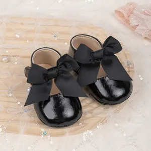 Detail of black patent leather baby Mary Jane shoes with a classic grosgrain ribbon bow