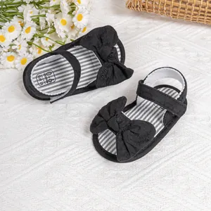 Close-up of black baby sandals with bow and black-and-white striped size insoles