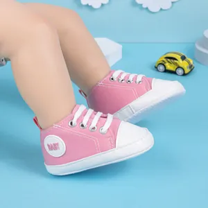 Vue détaillée des chaussures bébé en toile rose et blanc avec semelles souples en gomme