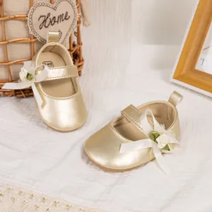 Golden baby girl Mary Jane shoes with ribbon bows and floral accents in cozy setting