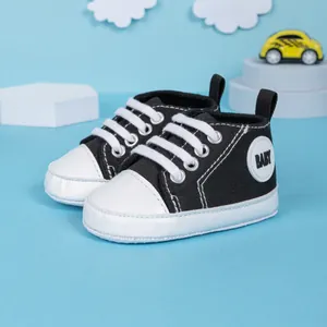 Chaussures bébé classiques en toile noir et blanc avec semelles souples sur fond bleu