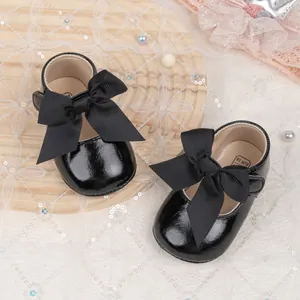 Detailed top view of black patent leather baby shoes with bow and pearl decorations