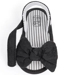 Close-up of black baby sandal with bow detail and soft striped inner lining
