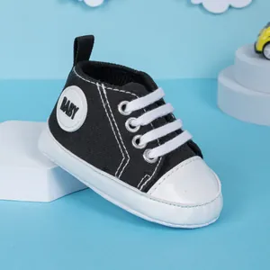 Détail de baskets en toile pour bébé avec lacets blancs et logo baby sur fond bleu