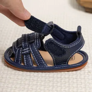 Detail of adjustable hook and loop strap on dark blue infant sandals with non-slip sole