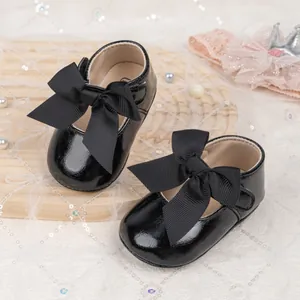 Close-up of baby princess shoes featuring black patent leather and a large grosgrain bow