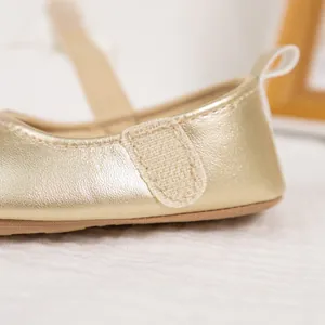 Detailed macro view of the golden baby shoes featuring secure velcro strap and shiny finish